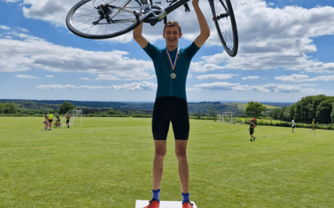 Student holding bike on gold winning stand