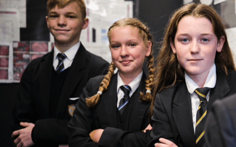 Three students in school uniform with arms crossed