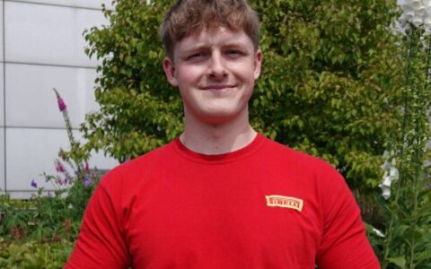 Former student, Ewan, smiling with foliage in the background